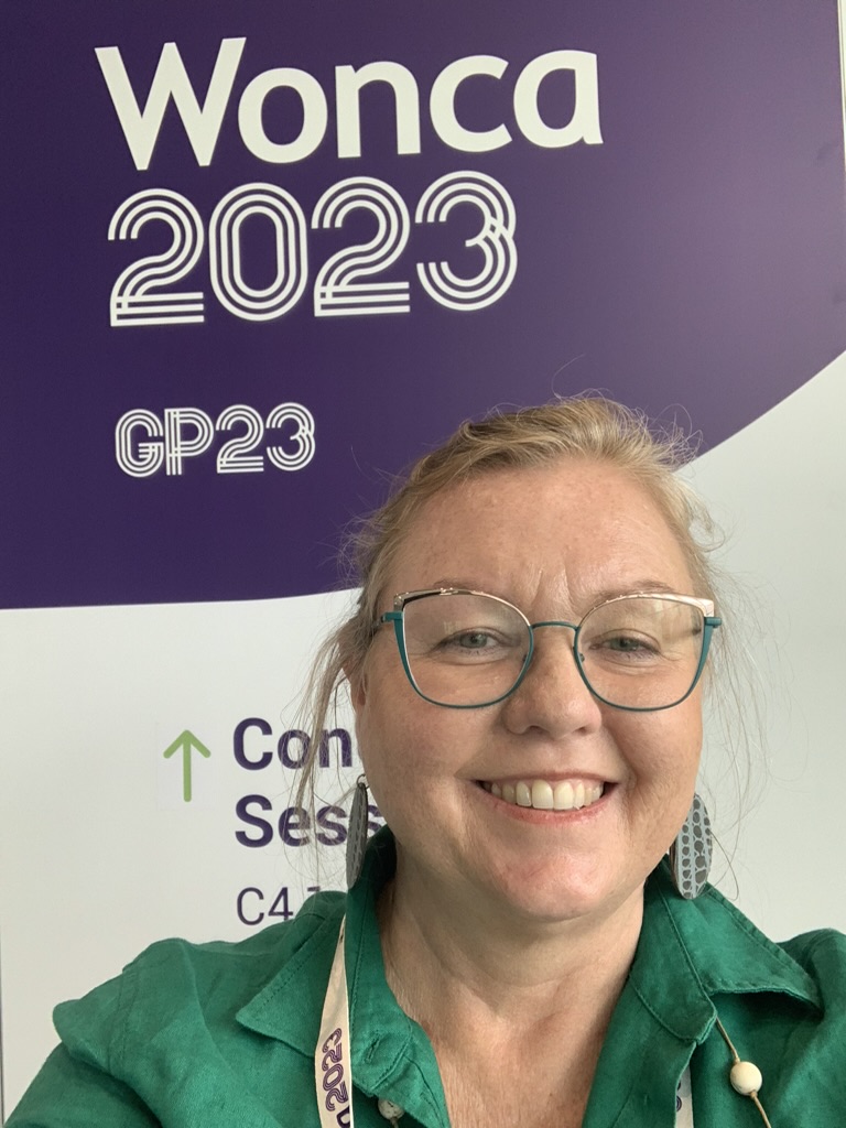 A delegate in front of the Wonca 2023 GP23 conference signage